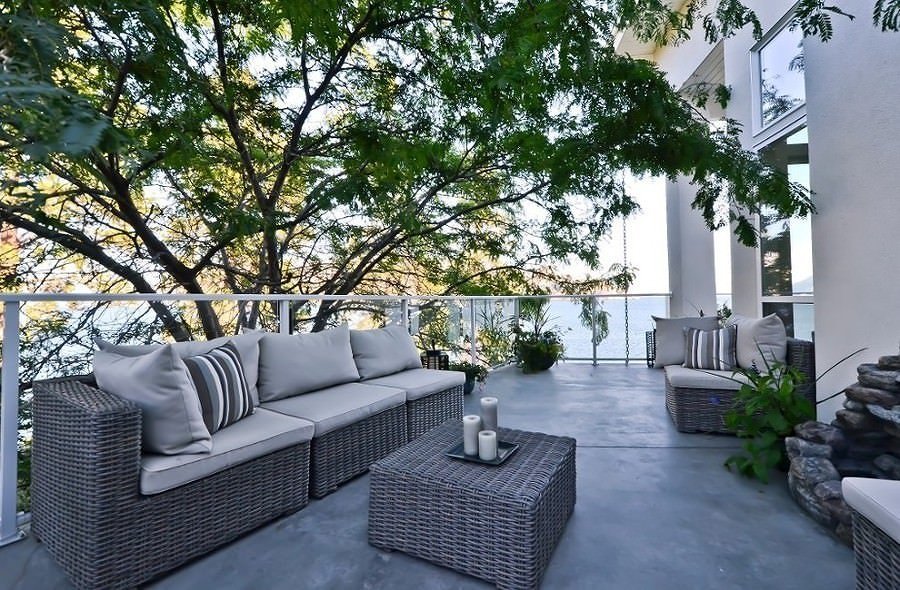 Piccolo terrazzo moderno ed elegante con pavimenti in calcestruzzo - arredi esterni in rattan colore bianco grigio, in sintonia con il pavimento della terrazza