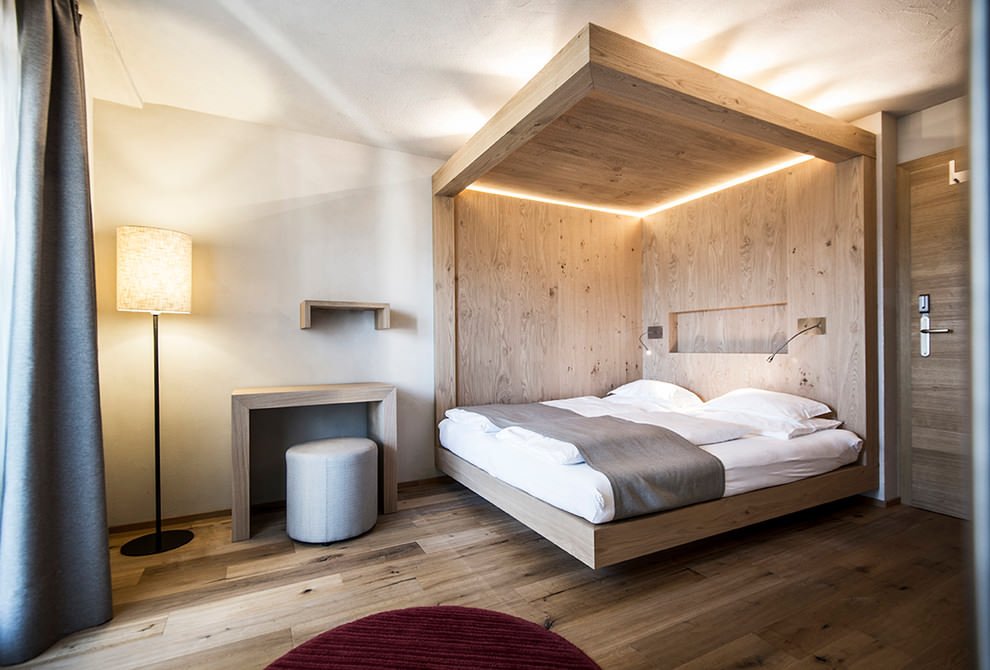 Originale camera da letto con baldacchino in legno - l’illuminazione a Led inserita nella parte alta e due applique collocate lateralmente - semplice ma di grande effetto
