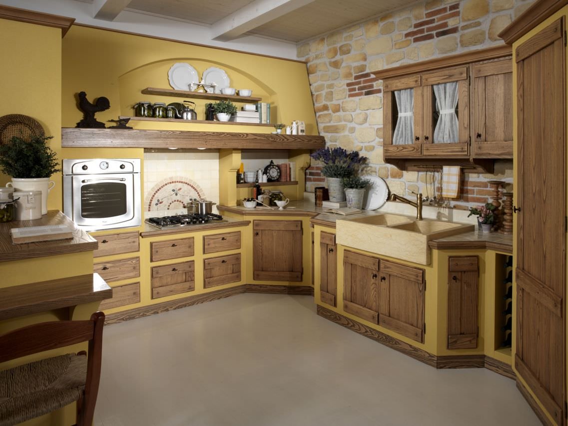 Progetto cucina in muratura classica - sportelli e cassetti in legno noce, parete rivestito in pietra e pavimenti in cemento, pareti di colore giallo