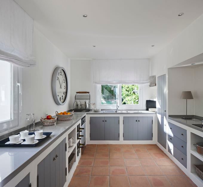 Piccola cucina in muratura classica realizzata con moduli fissi, top in marmo e sportelli colore grigio