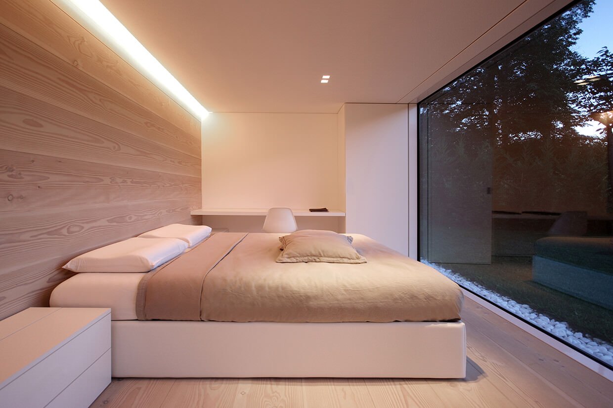 Bellissima camera da letto moderna che si affaccia sul giardino amplificando la percezione dello spazio con controsoffitto