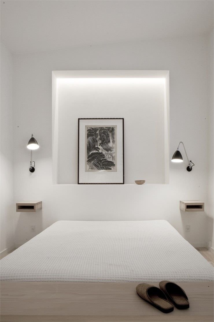 Camera da letto minimal con elegante nicchia illuminata che diventa cornice per un quadro. Idee lavori in cartongesso per la stanza.