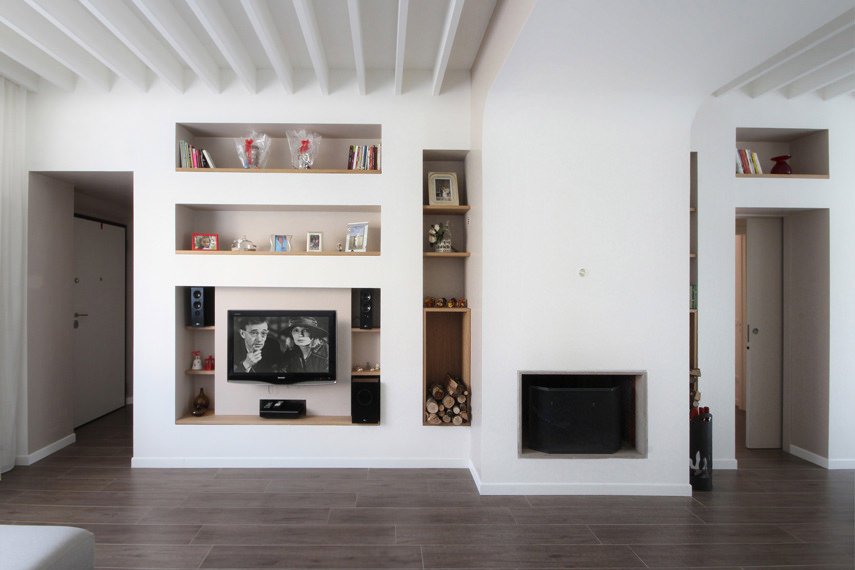 Soggiorno moderno con elegante parete attrezzata in cartongesso con mensole in legno, caminetto e travicelle verniciate sul soffitto.