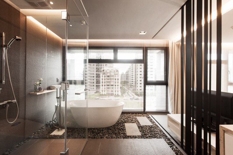 Stupendo bagno moderno con vasca e doccia in stile orientale zen integrato con la camera da letto che offre una bellissima vista sulla città attraverso una finestra lungo tutta la parete