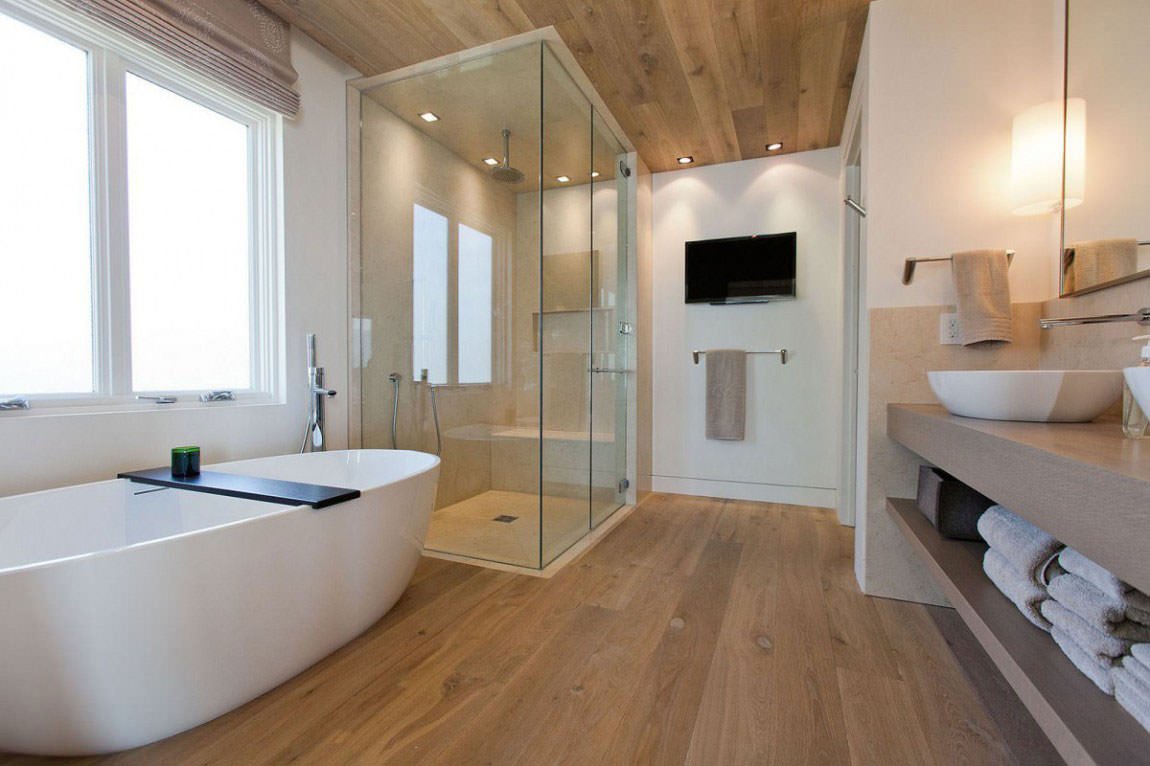 Luminoso bagno moderno con pavimenti e soffitto in legno, vasca in acrilico e box doccia in vetro e marmo e rivestimento a piastrelle - Start Preventivi