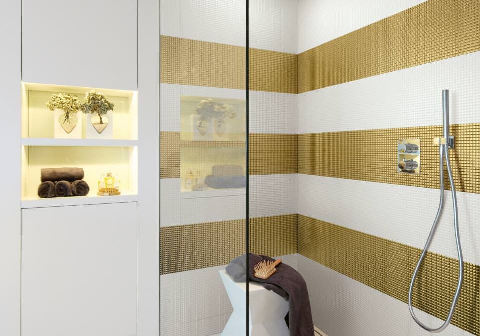 Dettaglio cabina doccia con rivestimento in mosaico a strisce orizzontali di colore bianco e oro