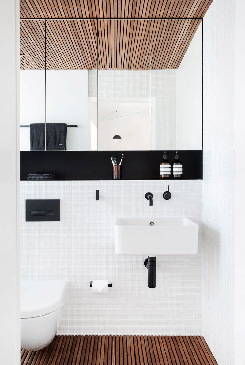 Superb modern minimal bathroom with striking contrasts and combinations: wooden floor and ceiling, white mosaic covering, in contrast with the niche and some black details, the cabinet with mirrored doors along the entire wall.  Original idea to renovate bathroom.