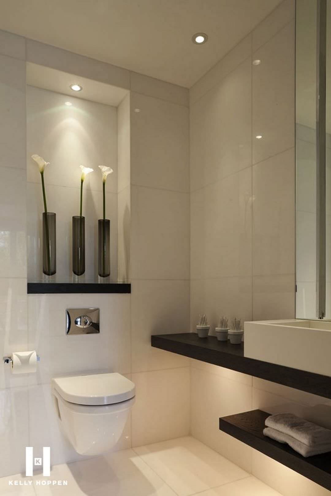 Detail of luxury bathroom, modern and elegant, with an illuminated niche obtained above the sanitary, enhanced with three decorative elements.  Floor and wall tiles made of large tiles.