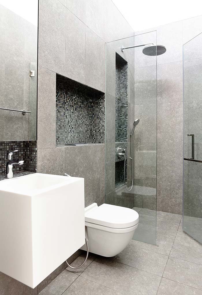 Idea piccolo bagno moderno con pavimento e rivestimento in piastrelle di gres porcellanato di grandi dimensioni, fino al soffitto. Molto interessante la soluzione della nicchia sopra la cassetta del wc, con due ripiani che si prolungano oltre il confine del muro