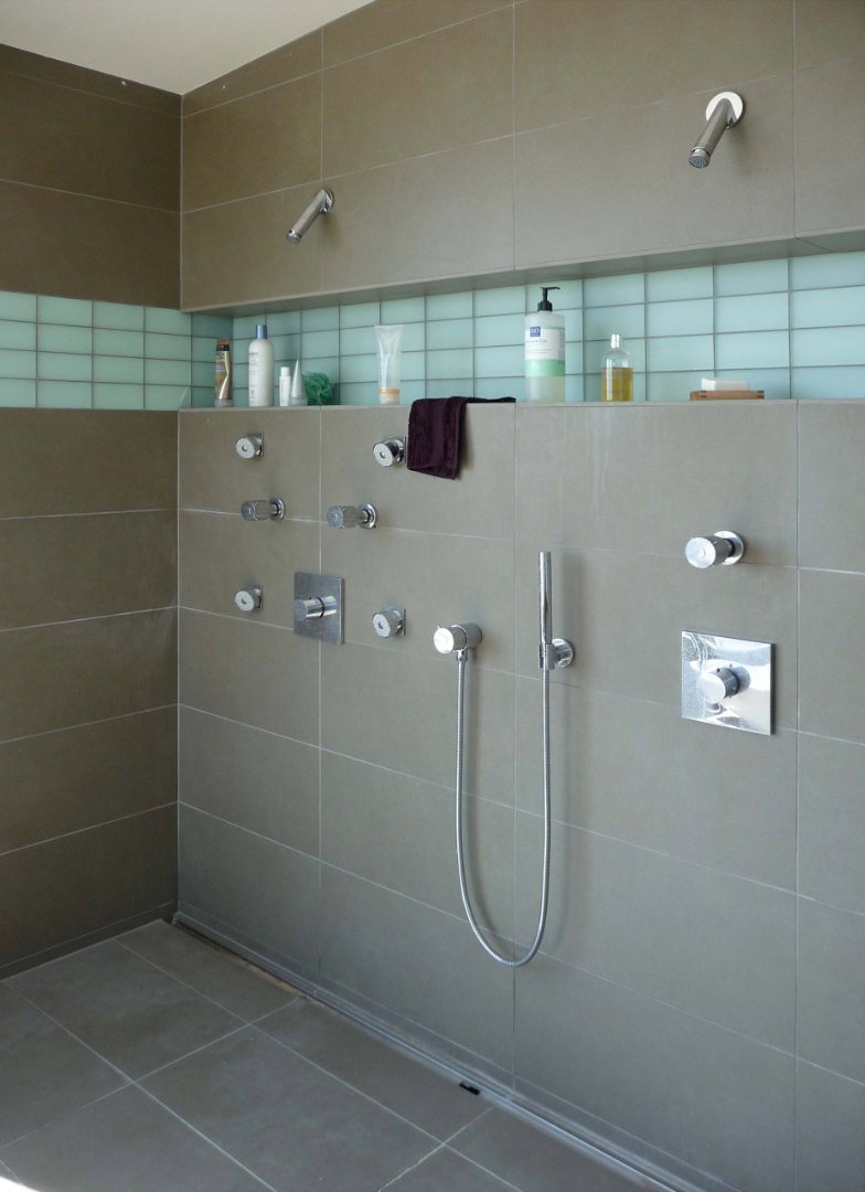 Doccia con nicchia orizzontale, all’altezza della testa, realizzata in piastrelle blu, in contrasto con il colore del gres delle pareti. Idee rivestimento bagno