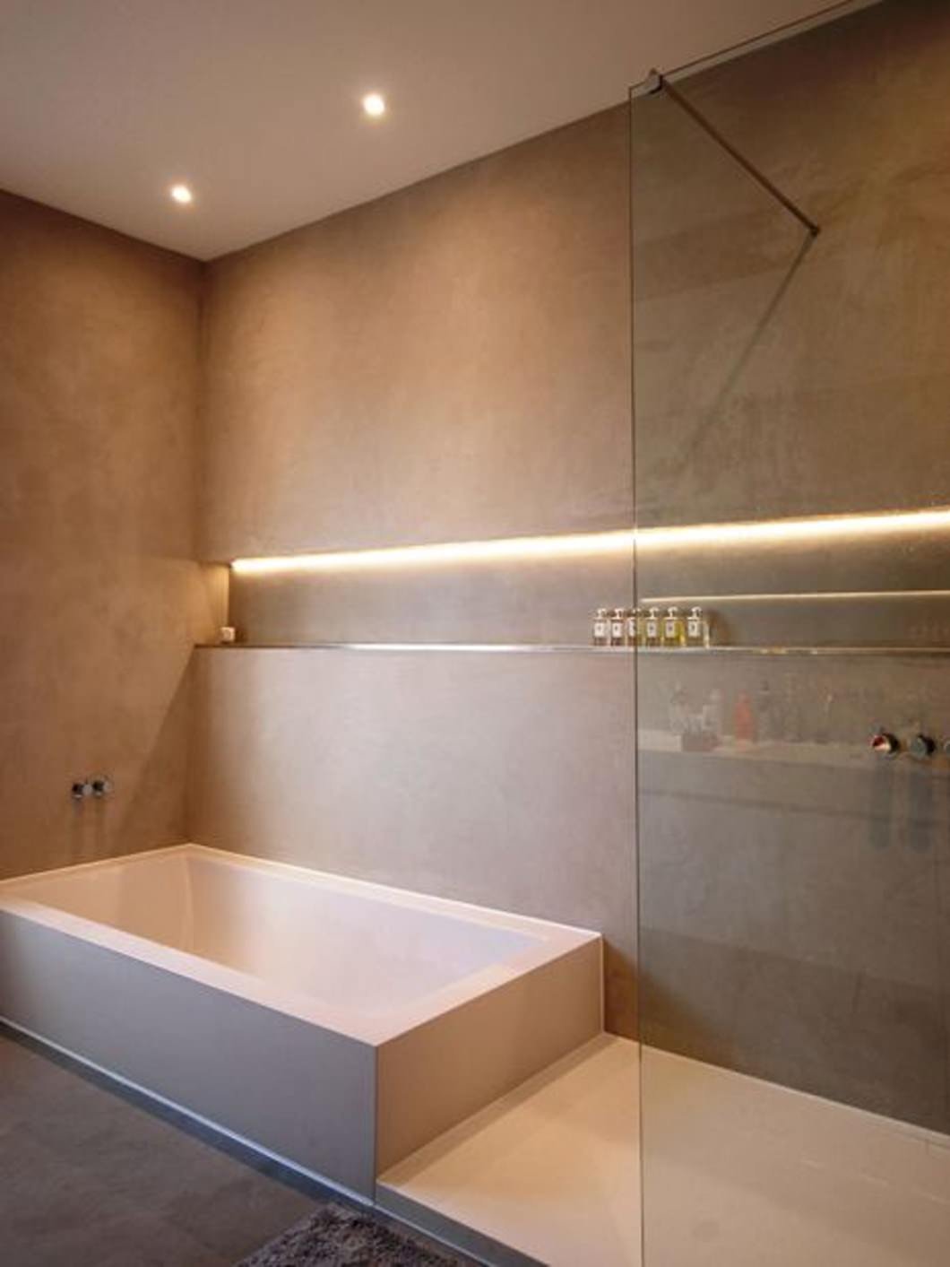 A nice example of a modern bathroom with storage niche along the entire wall of the shower / tub.  The led light from depth and warms the space.  Resin floor and coating.