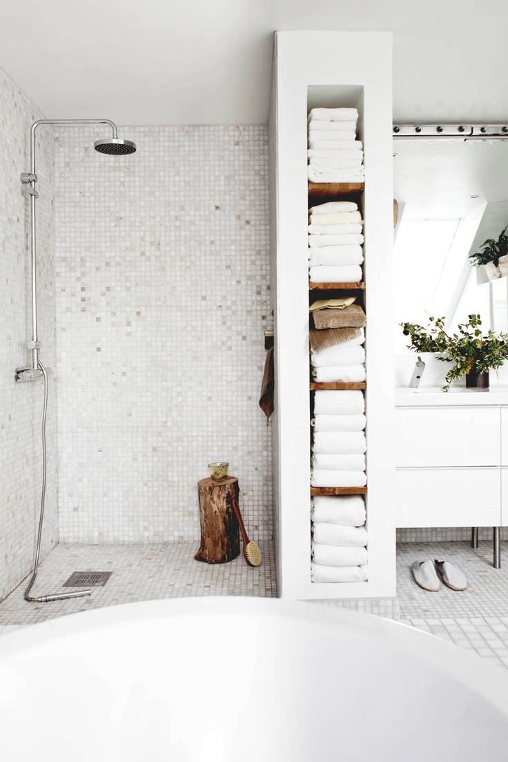 Immagine bagno scandinavo con armadio creato in muratura. Pavimento e rivestimento in mosaico di colore bianco. Ambiente luminoso e pulito. Idee ristrutturare bagni.