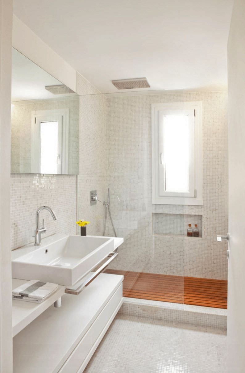 Modern and elegant bathroom with mosaic floors and walls.  A wooden platform has been installed on the shower tray, a solution highly appreciated for its comfort and safety.