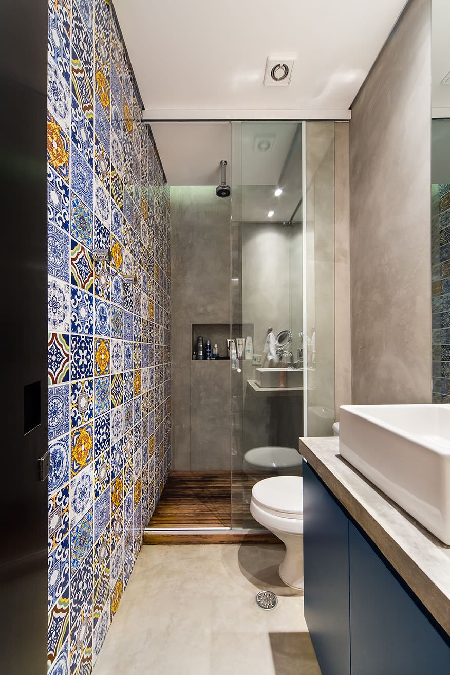 Piccolo bagno con pavimenti e pareti in resina ed una parete rivestita in piastrelle patchwork che donano profondità alla stanza.