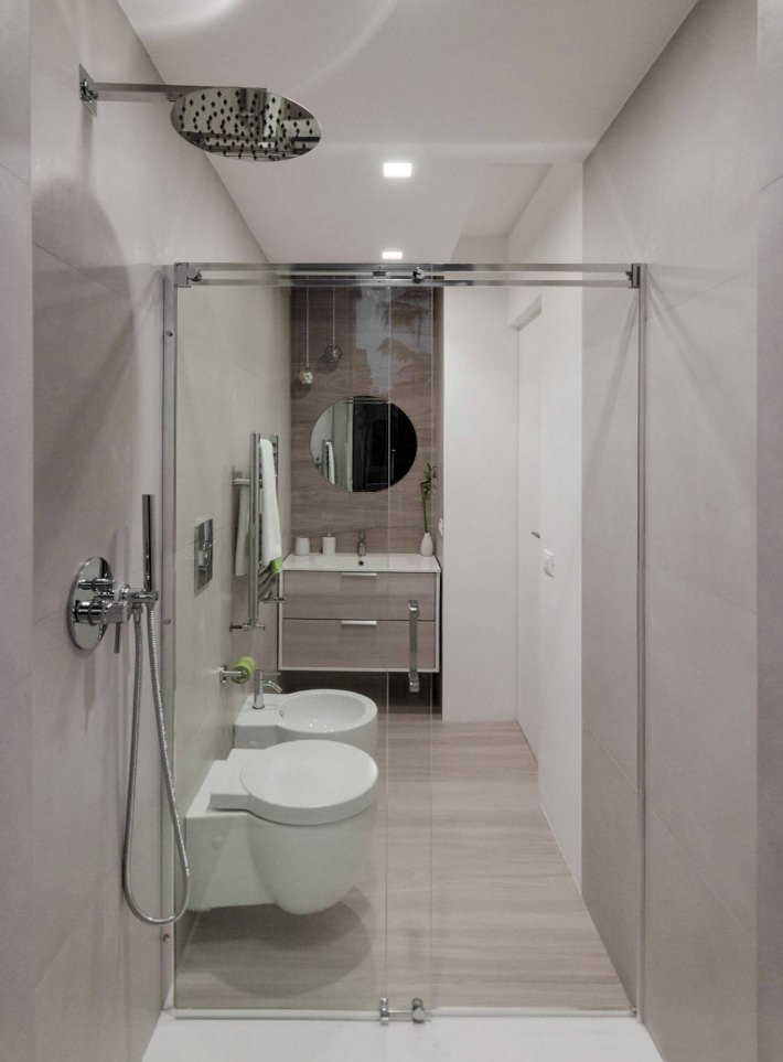 Immagine piccolo bagno moderno ed elegante con sanitari di dimensioni ridotte. Parete centrale e pavimento in piastrelle simile legno ed il rivestimento in lastre di gres porcellanato.