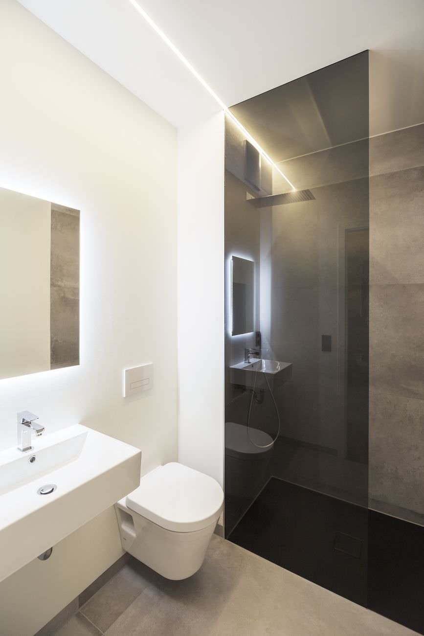 Ispirazione per un bagno piccolo, moderno, elegante e luminoso. Una striscia di luce led è stata inserita nel controsoffitto in cartongesso. Lo stesso sistema è presente sul perimetro dello specchio per un bellissimo effetto. Doccia a filo pavimento con il vetro nero sfumato. Pavimenti e rivestimento in marmo - progetto per ristrutturare bagni moderni piccoli