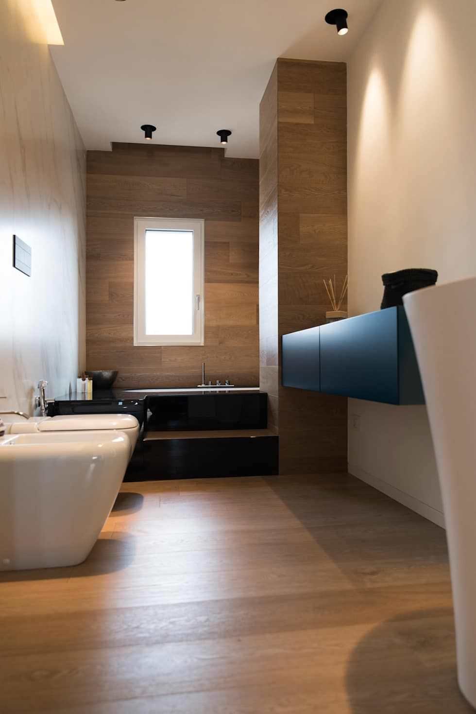 Bagno piccolo moderno ed elegante con pavimenti e rivestimento in legno ed una bellissima vasca. Colori a contrasto: bianco e nero.