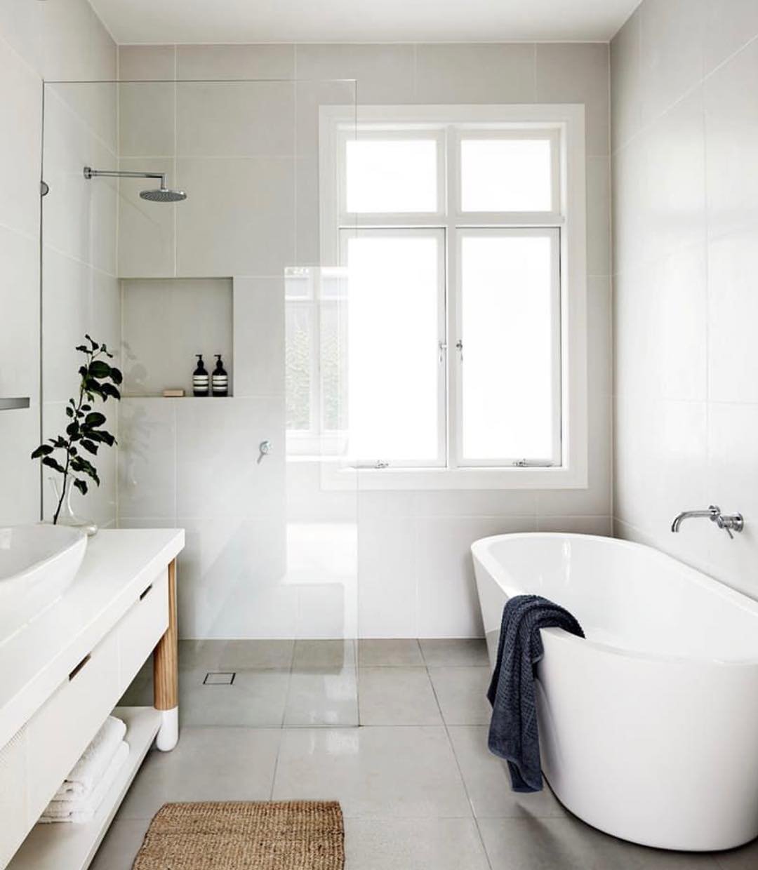 Idea piccolo bagno con vasca e doccia, stile scandinavo, luminoso e pulito. Spazio perfettamente studiato per la massima ergonomia. Pavimenti e rivestimenti in ceramica di grandi dimensioni.