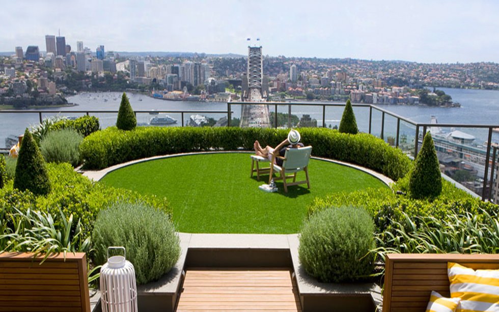 Bellissimo terrazzo in cui il panorama fa da padrone - vari piante verdi ben curate e pavimento in erba sintetica completano l'atmosfera - idea per pavimentazione terrazzi esterni, alternativa alle mattonelle e piastrelle