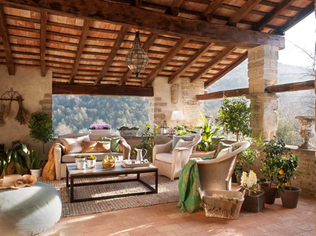 Terrazzo rustico mediterraneo con i pavimenti in argilla - arredi color crema e perfetto connubio tra legno e pietra - idee per pavimentare terrazzi esterni alternativa alle piastrelle e mattonelle