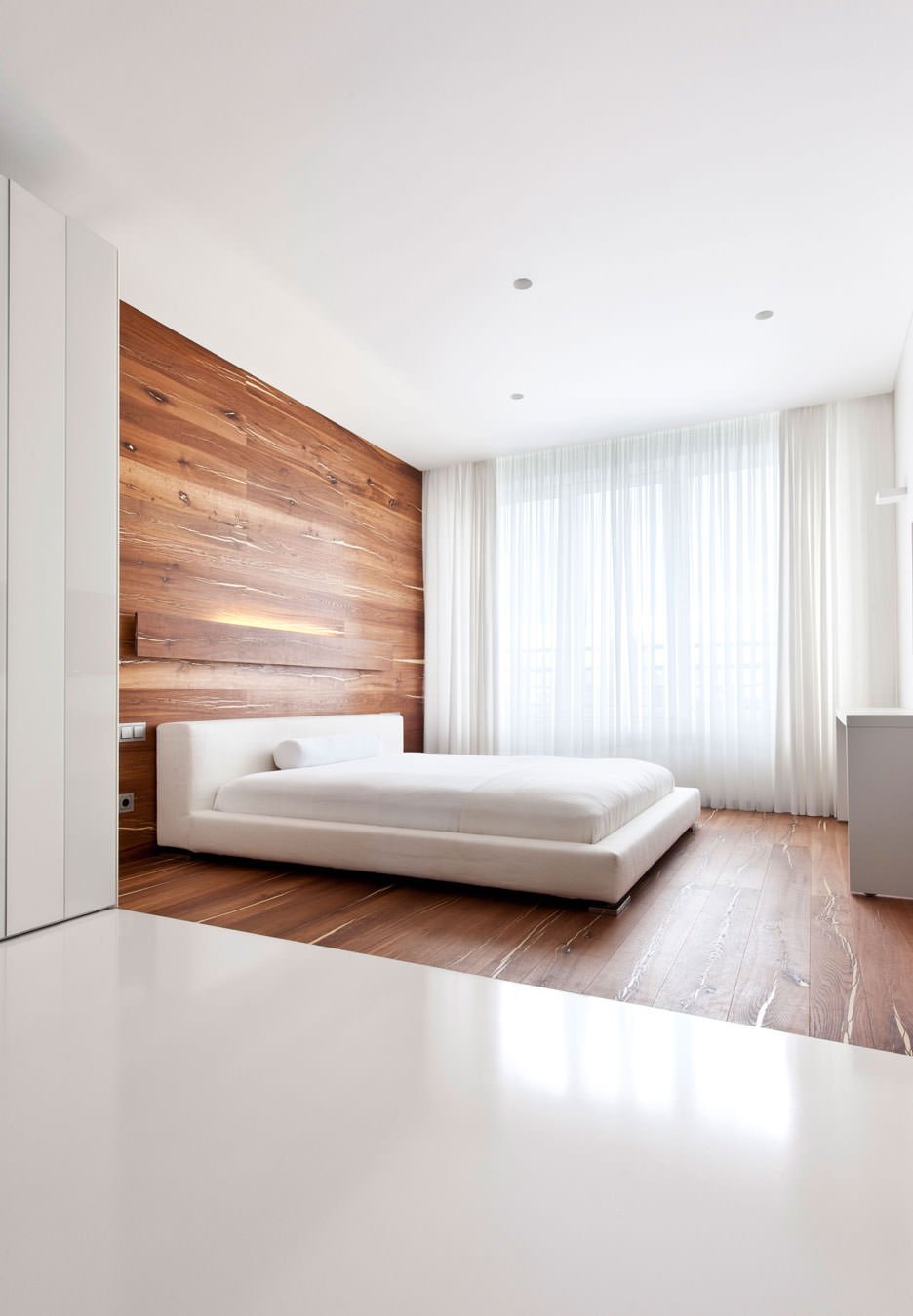 The floor extends over a portion of the wall, differentiating the area read from the rest of the environment.  Modern minimal style - white in contrast with wood