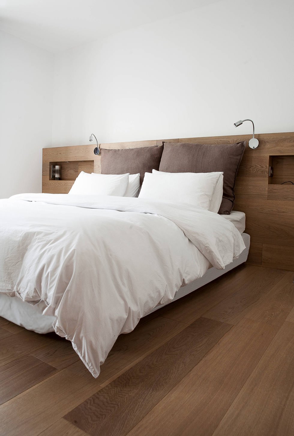 Bedroom with minimal modern lines with oak wood headboard.  White and brown colors