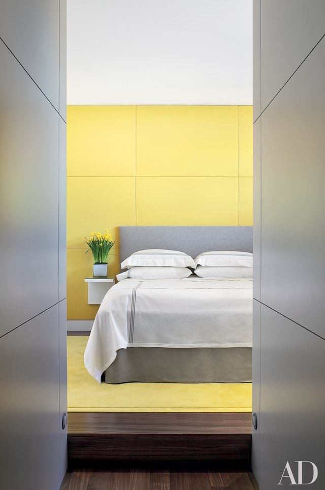 Camera da letto moderna con rivestimento parete in pannelli in PVC di colore giallo e testata in tessuto grigio - elegante e raffinata. 