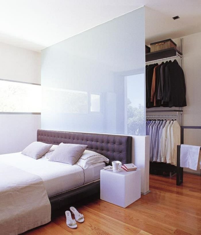 Superb modern bedroom where the tempered glass headboard creates a walk-in closet.  The furniture makes the architecture of the room.  Wooden floor.