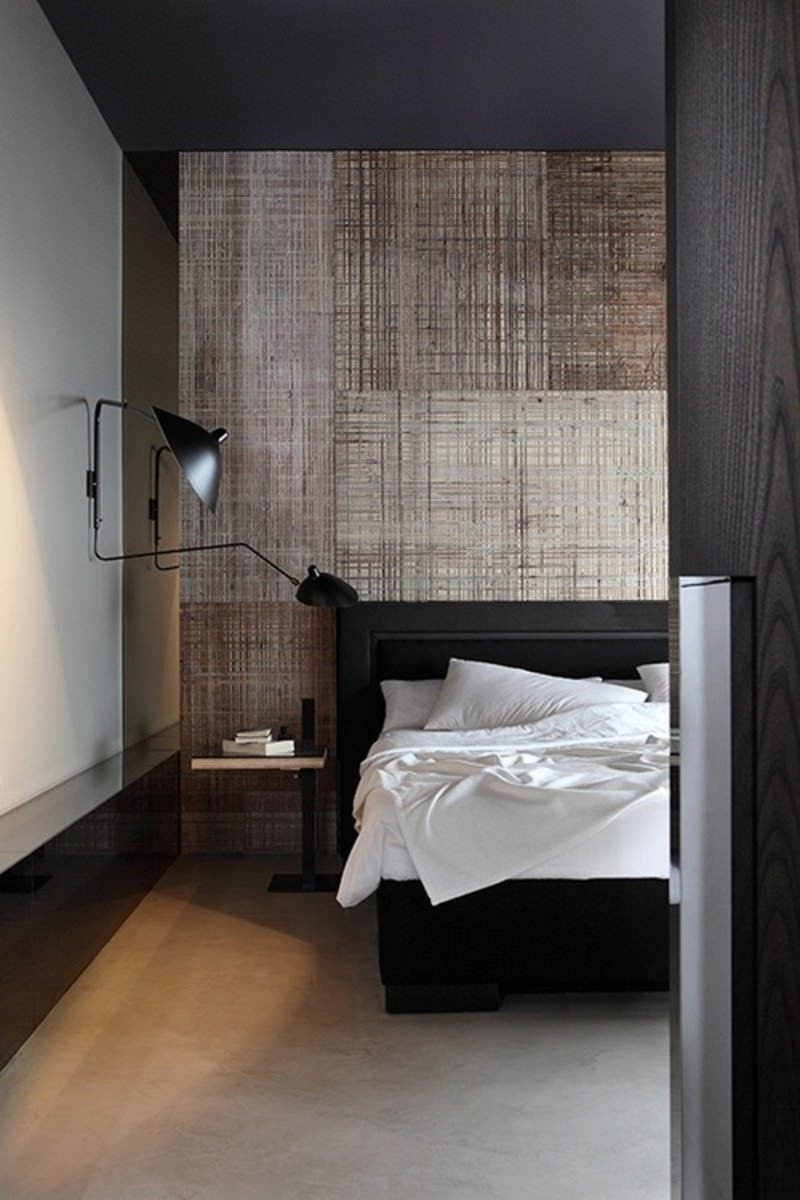 Modern bedroom with elements that express the male presence.  The headboard wall, the very essential black furniture, the clean line of the lamp and the dresser communicate a perfect organization - concrete floor - white, black and brown colors.