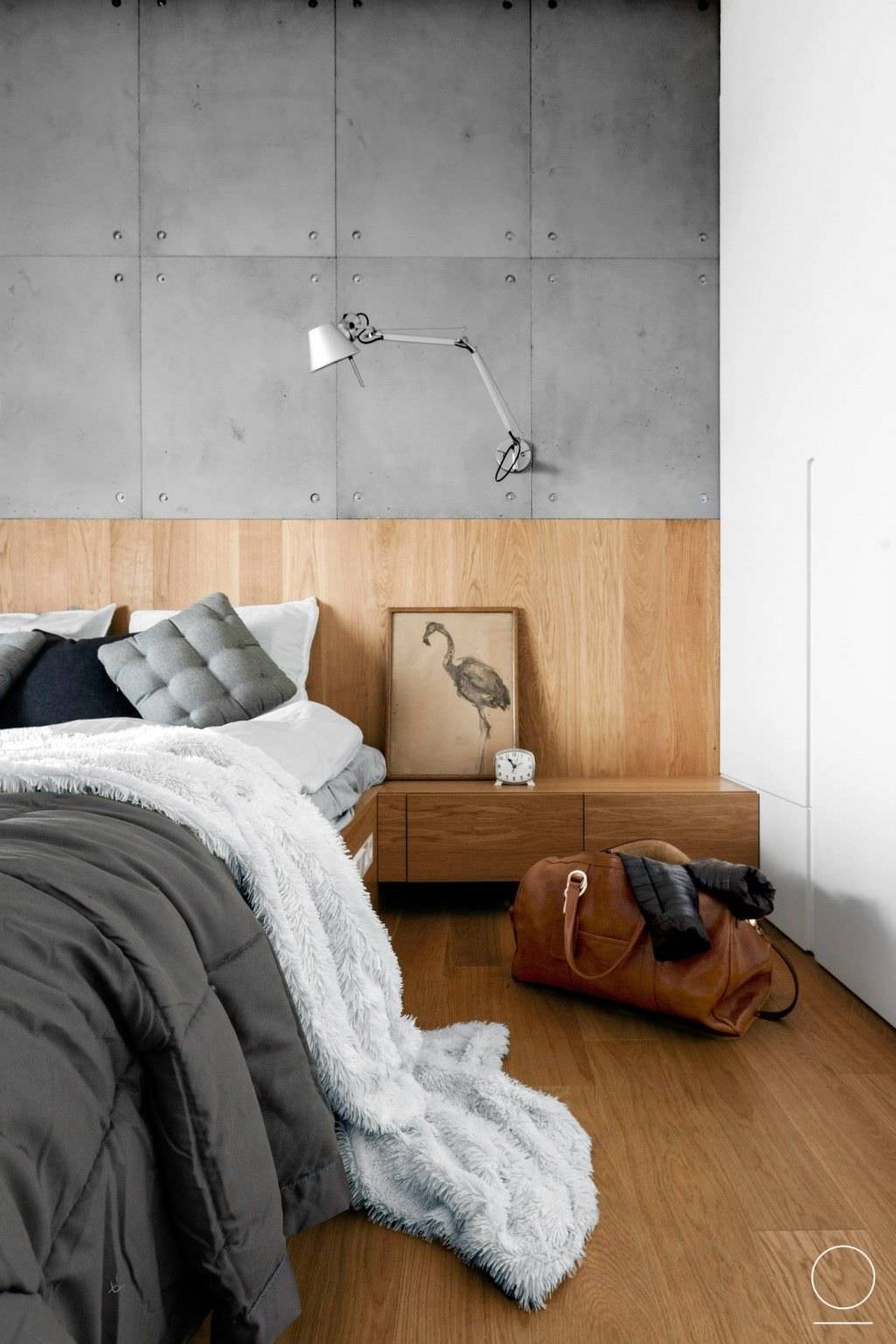 Modern bedroom with a style that varies between the minimal of the concrete paneled wall, the Scandinavian oak wood of the floor and the headboard, expresses a strong and elegantly masculine character.