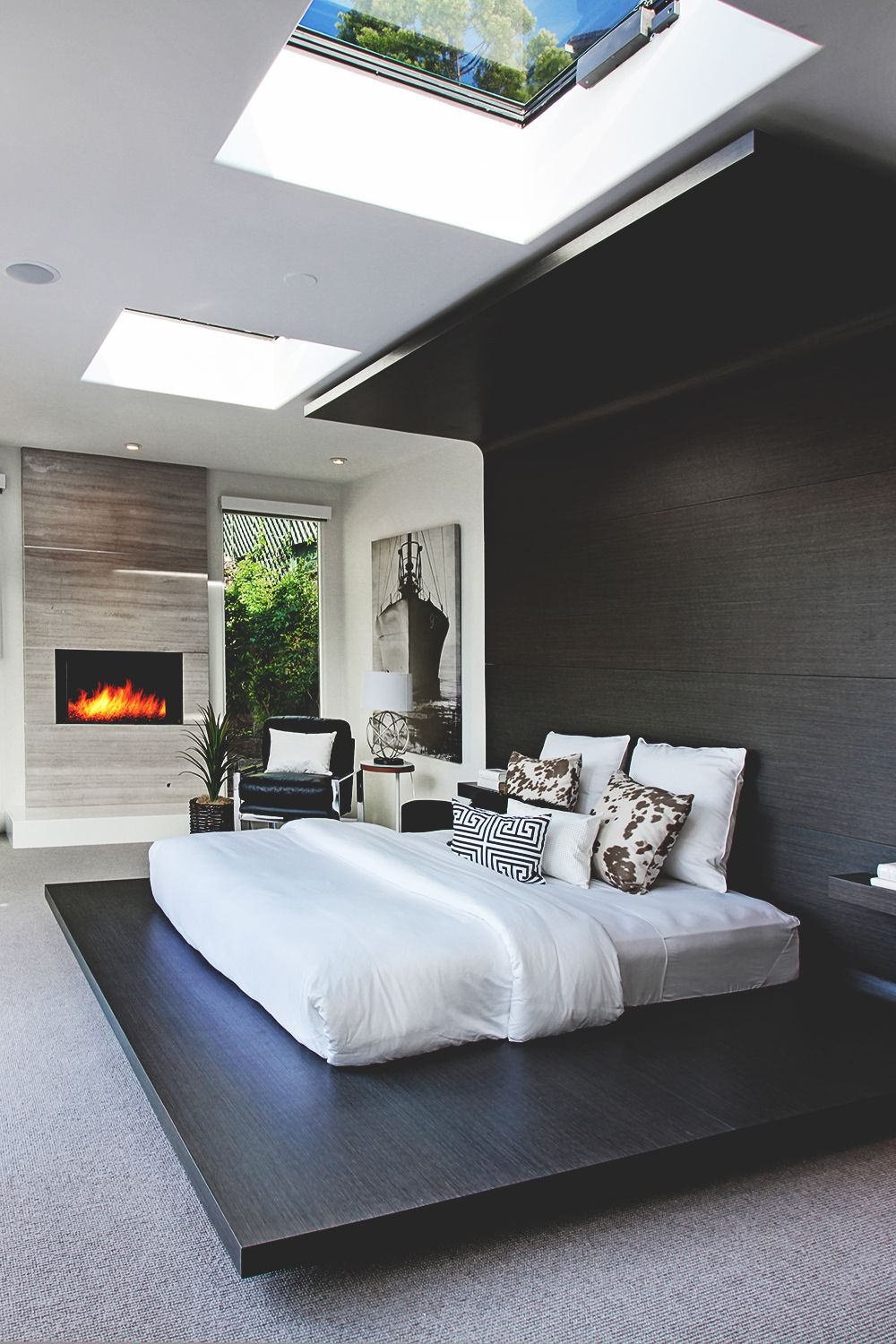 Modern bedroom, masculine style, very original and with an exquisite design.  A wooden structure wraps the bed, reduced to a mattress only - large windows on the ceiling for a perfect view - open fireplace with marble cladding