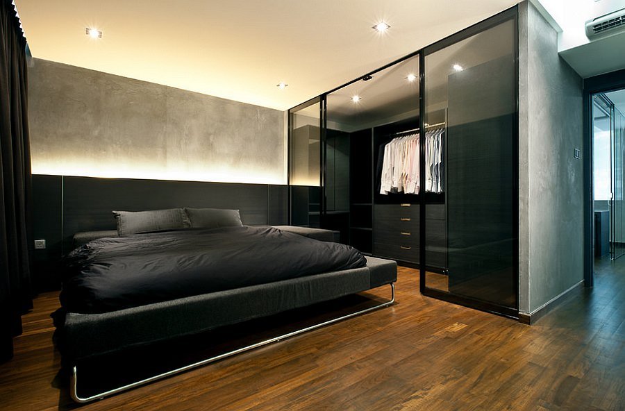 Modern bedroom with dark wood finishes, brushed parquet, pure contrasts that communicate virility and masculinity.  The walk-in closet with glass panels reinforces the idea of ​​transparency.