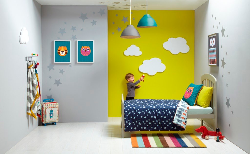 Idea piccola cameretta bambini molto allegra e colorata - colori giallo, blu e grigio - stickers a forma di stelle per decorare pareti e soffitto - pavimento bianco in laminato