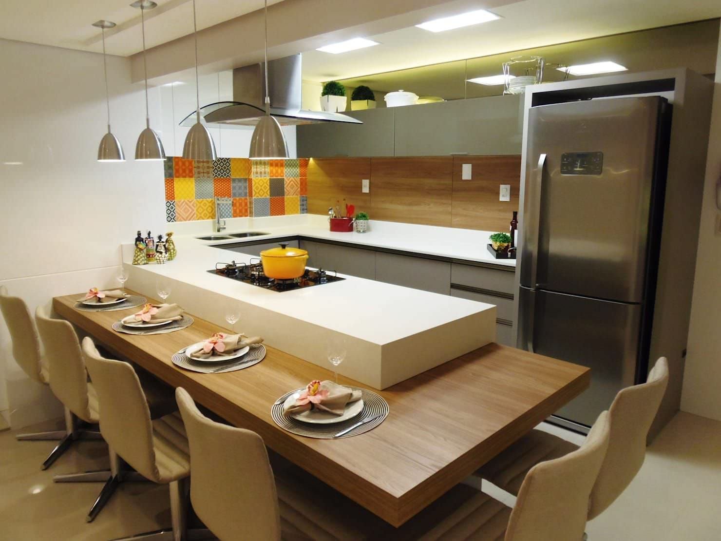 Cucina con isola inglobata in un mobile, disposto lungo un piano in legno. Idee cucine con penisola