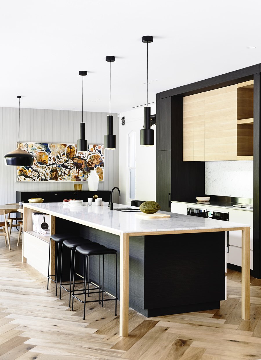 Progetto per cucine con isola realizzate in un contrasto di bianco e nero abbinati al legno dei mobili e del pavimento. Ambiente open space. Il top diventa un vero tavolo, abbastanza capiente per l'intera famiglia.