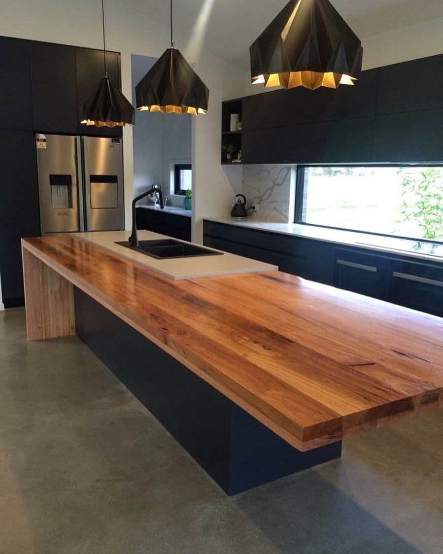 Idee cucine dello stile moderno industriale - isola con top in legno massello, mobili di colore nero, pavimento in cemento, paraschizzi creato da una finestra lunga tutta la parete. 