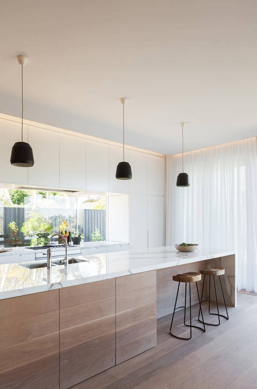 Cucina scandinava con mobili in quercia e top in marmo bianco. Parete attrezzata in laminato con paraschizzi a finestra. Illuminazione diffusa a led sul soffitto.