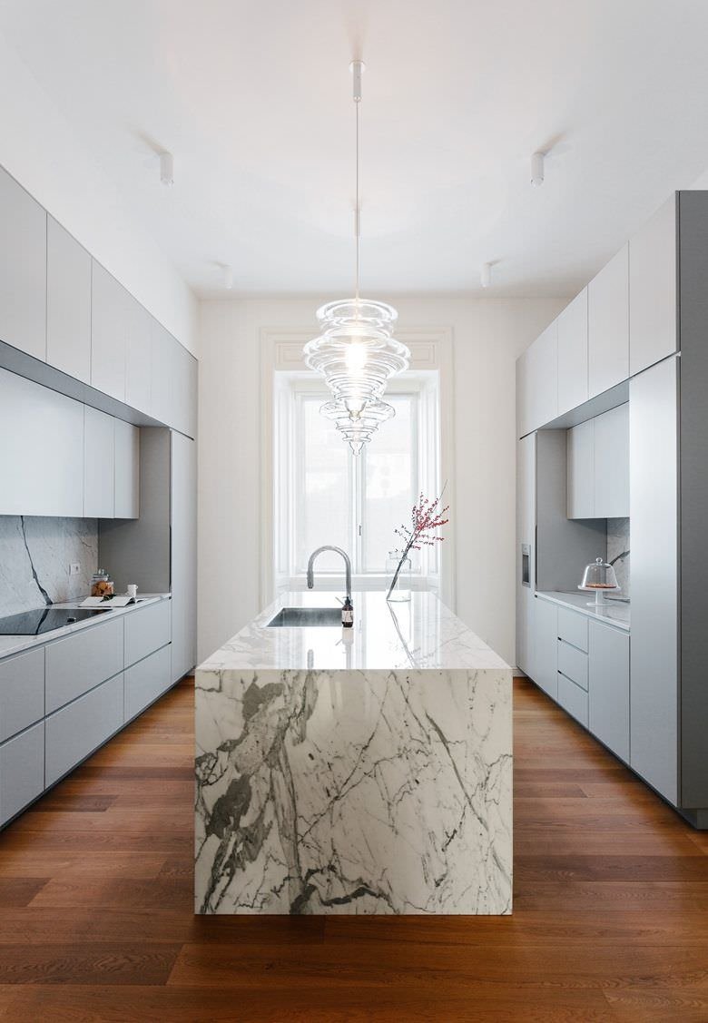 Stupenda cucina moderna con isola in marmo e mobili in laminato grigio. Pavimento in legno.