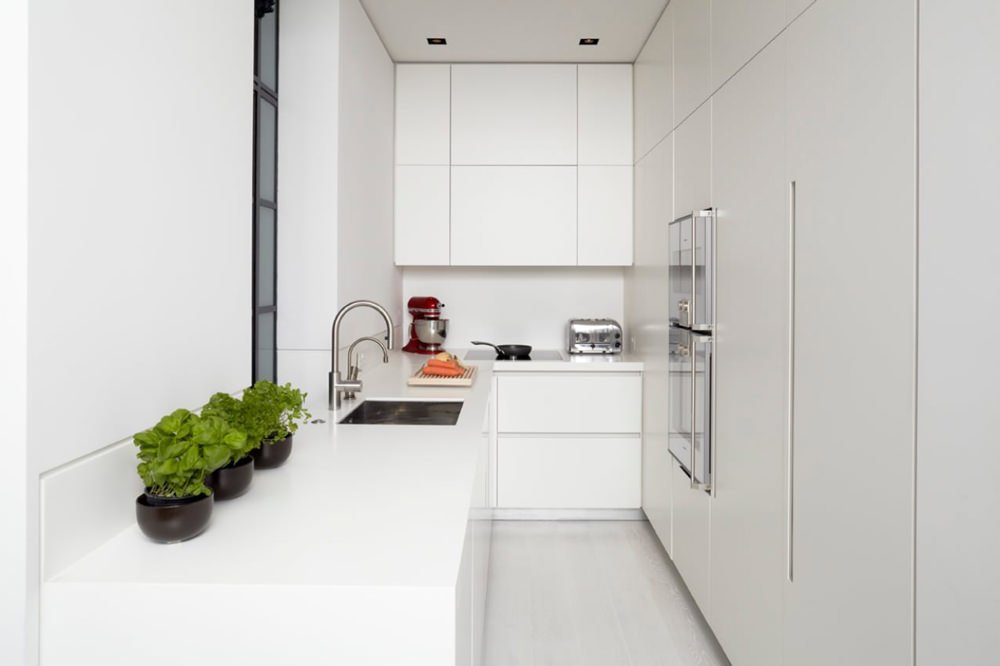 Bellissima cucina bianca piccola a corridoio, stile moderno minimal. Mobili e ante in laccato, pavimenti in laminato bianco.