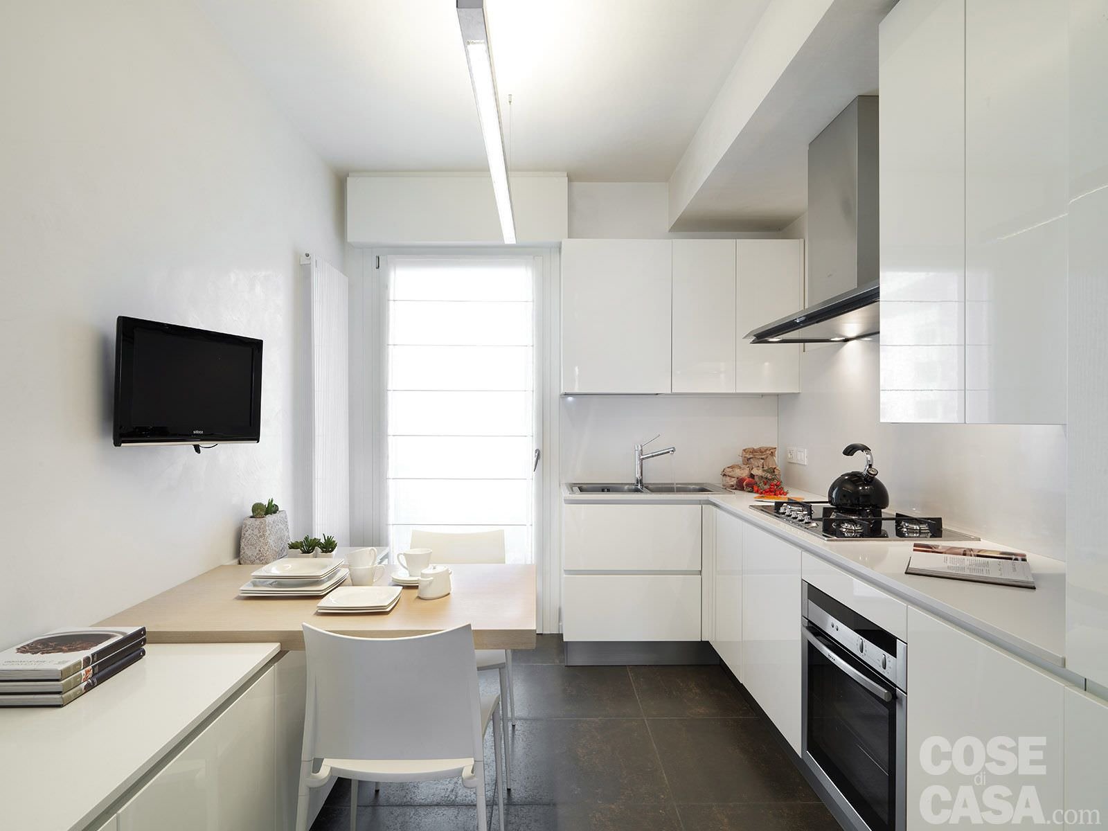 Piccola cucina moderna con i mobili in laccato bianco per aumentare lo spazio visivo. Pavimenti in gres porcellanato. 