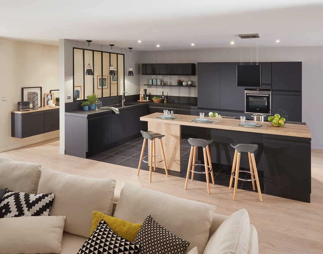 Cucina moderna open space in nero e legno. Il pavimento in gres grigio scuro separa visivamente questa zona dal soggiorno.