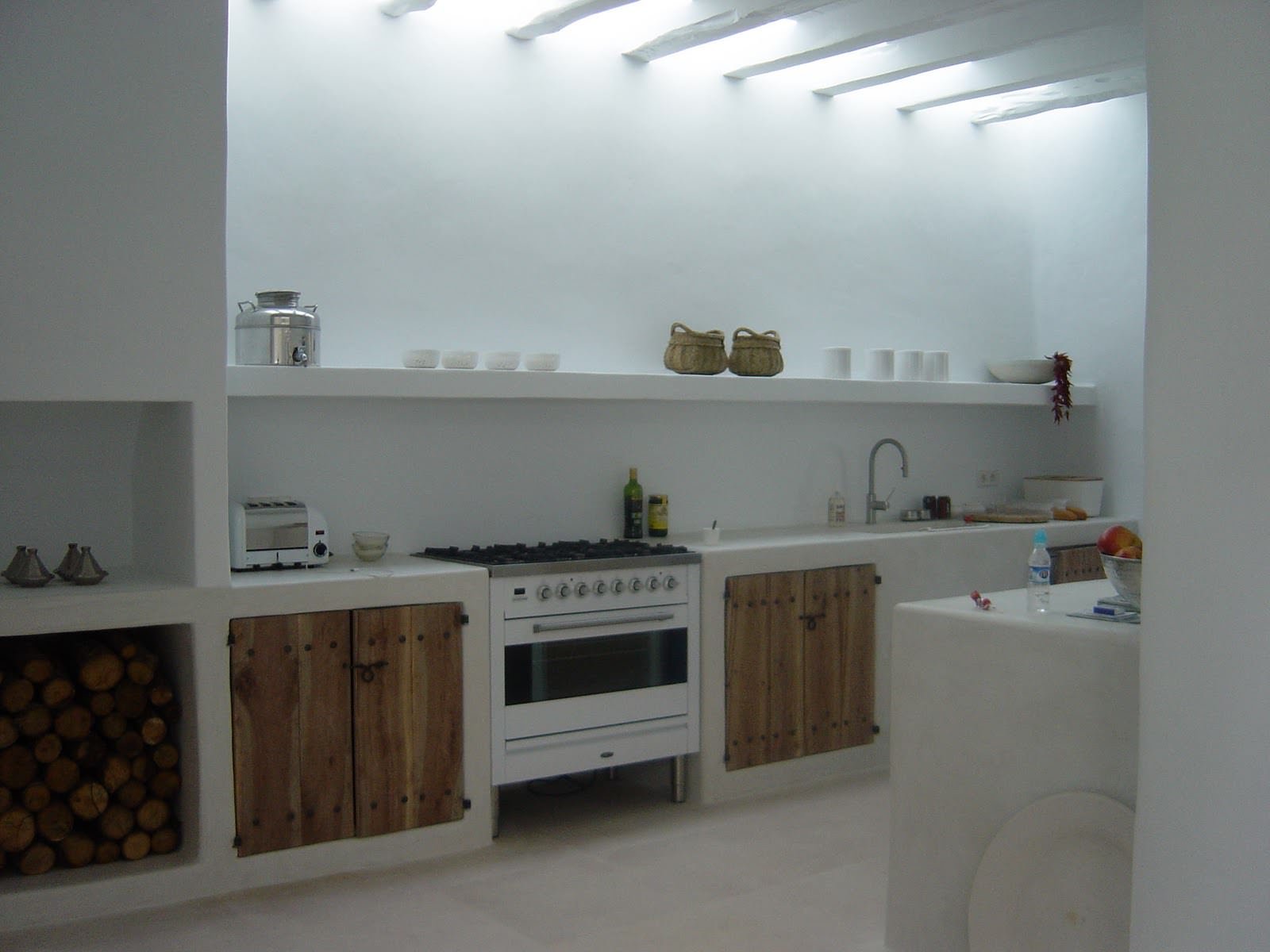 Stupenda cucina rustica moderna, semplice e lineare: sportelli in legno grezzo,  pavimenti in travertino e soffitto e pareti dipinte in bianco - piccolo camino aperto