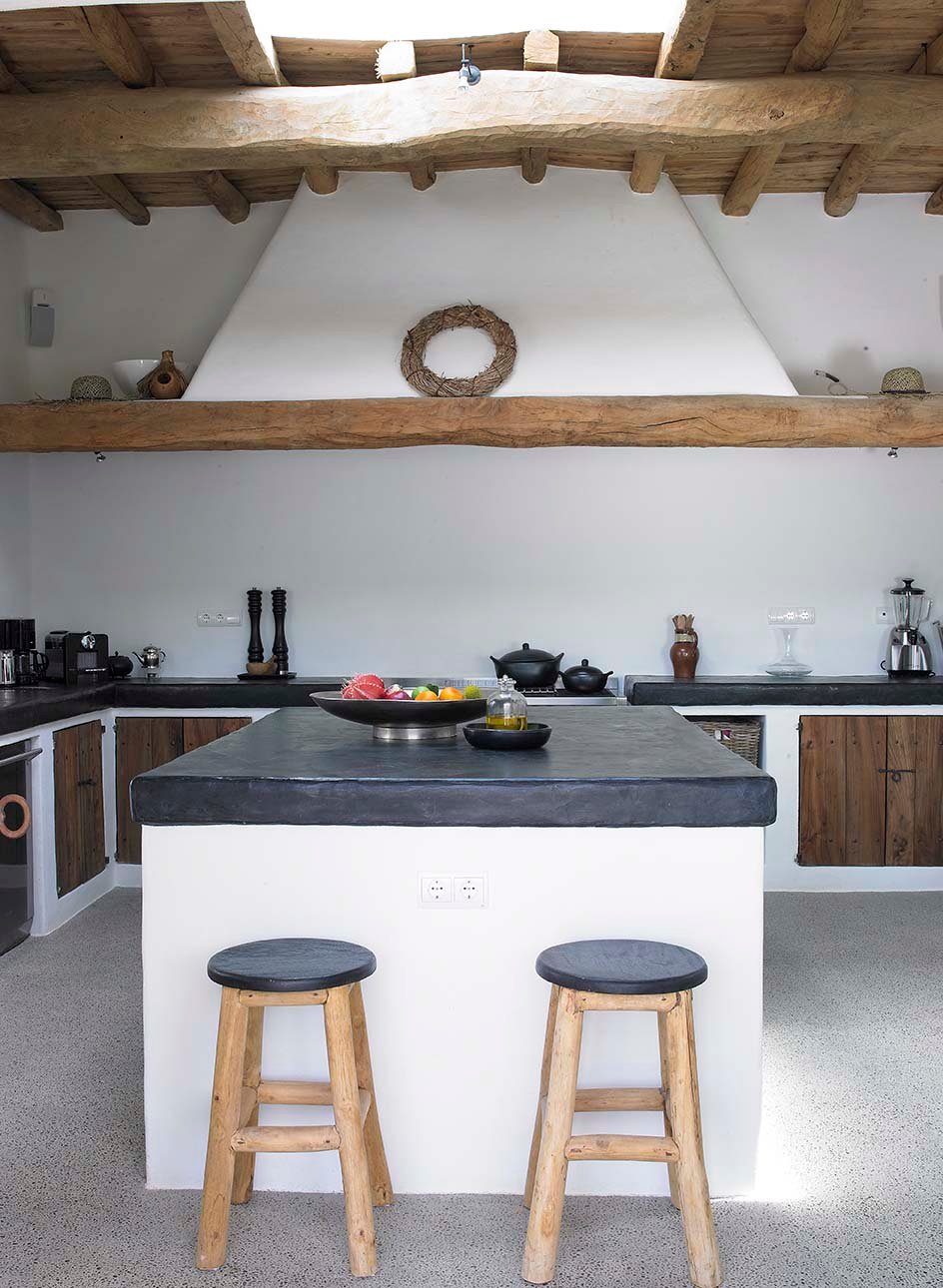 Bellissima cucina in muratura rustica, con isola centrale - abbinamento colori bianco, nero e legno - soffitto con travi in legno e pavimenti in cemento - confronto preventivi muratore