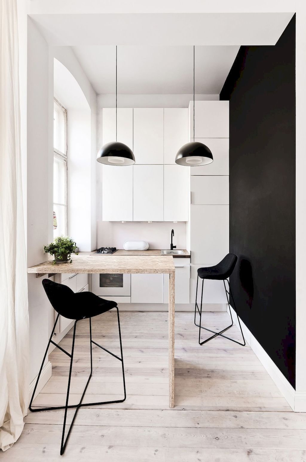 Stupenda cucina piccola da grandi armonie in cui la dominanza del bianco contrasta fortemente con la parete in vernice nera. Il parquet in legno chiaro dona carattere ed eleganza allo spazio.