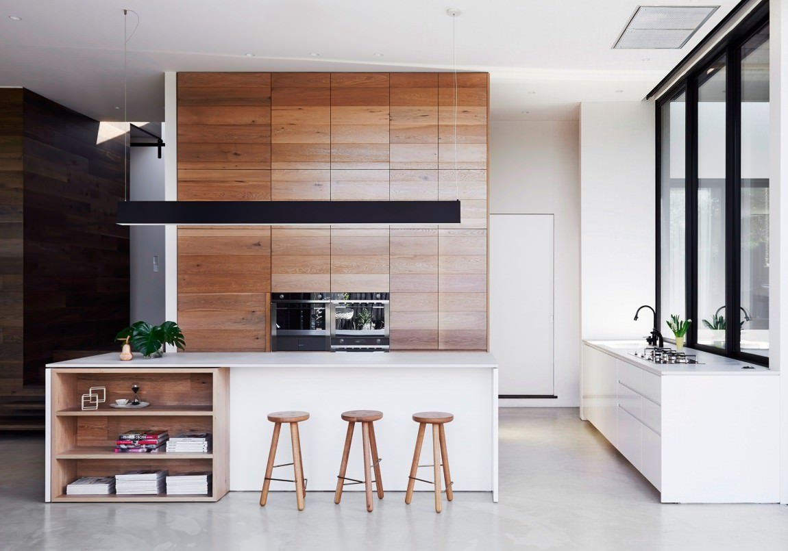 Cucina moderna minimal definita con falegnameria in rovere, banco realizzato in pietra colore bianco e accenti neri