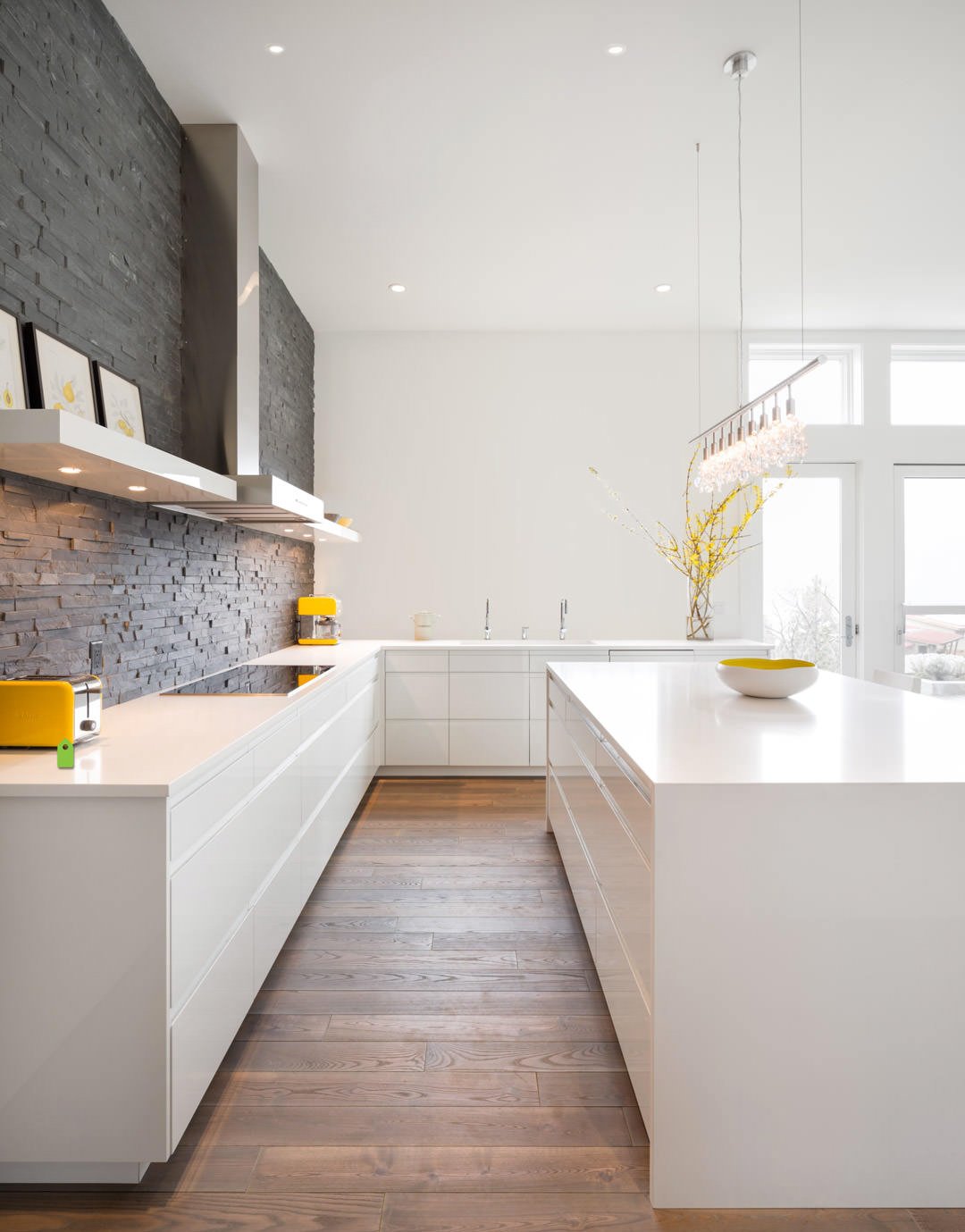 Cucina con muro in mattoni scuri perfettamente abbinato ai mobili bianco lucido e al pavimento in massello - Idee cucine moderne