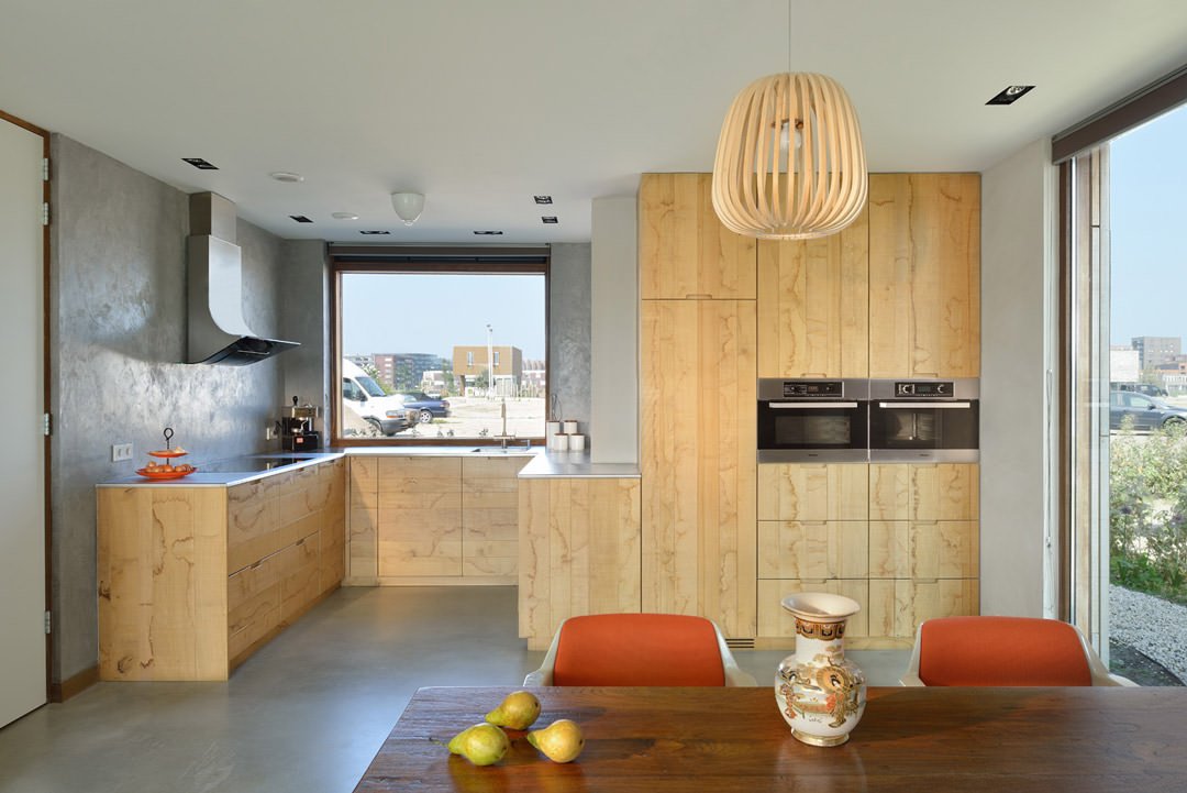 Cucina piccola moderna con pareti di cemento e mobili in legno. Molto luminosa e originale