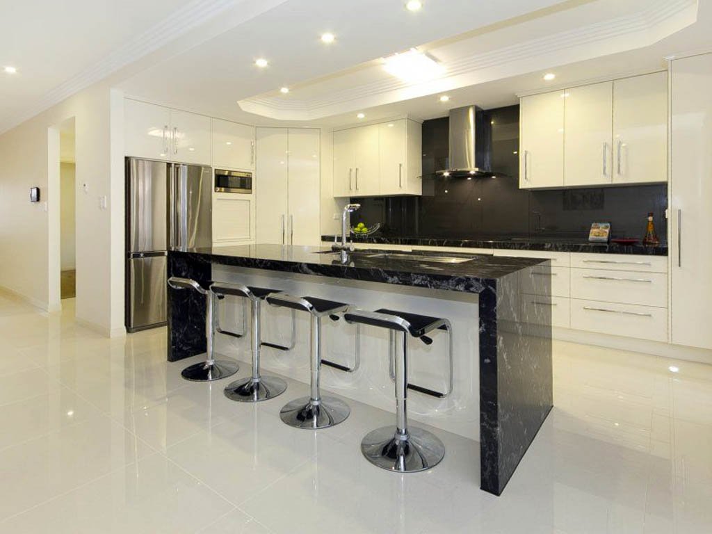 Cucina contemporanea in bianco e nero con isola - top e paraschizzi rivestite in granito ed il pavimenti in marmo bianco, ambiente elegante e moderno - idee mattonelle per cucine di lusso