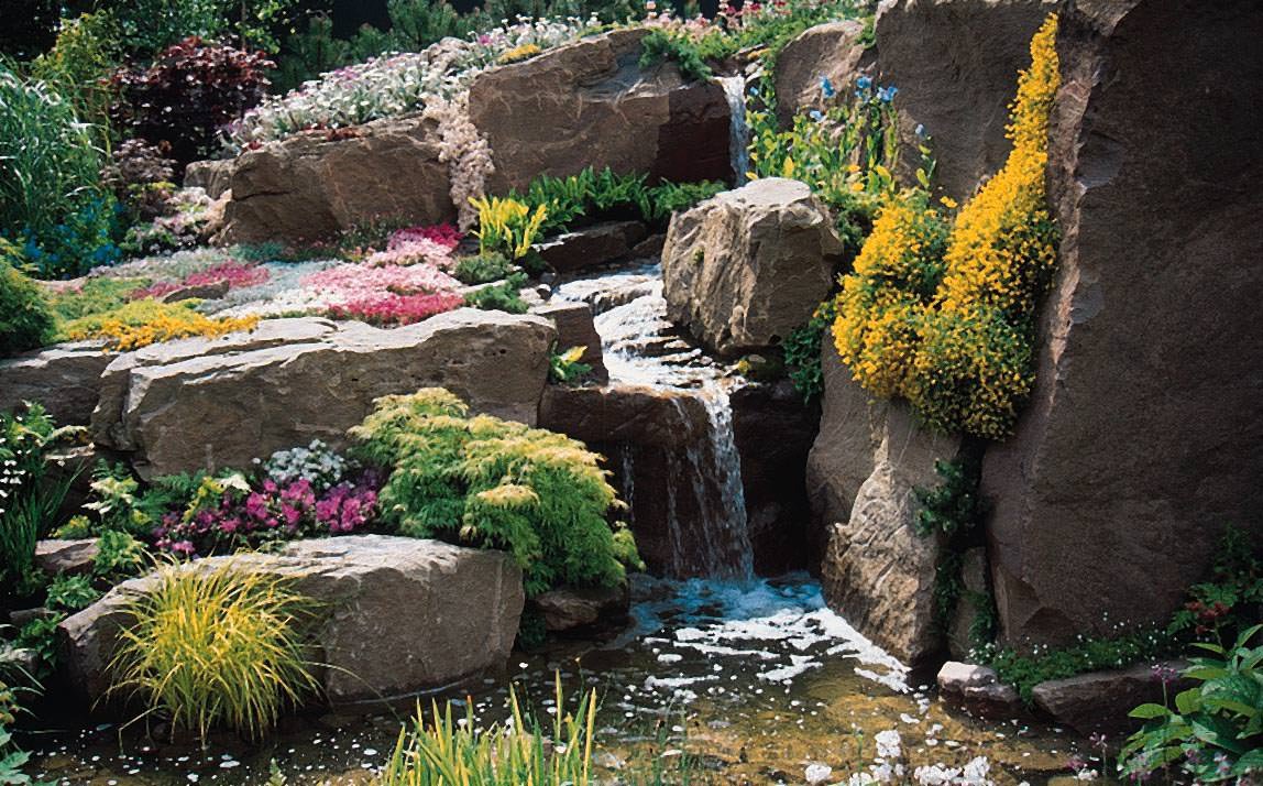 Ispirazione per creazione giardini rocciosi con cascata d'acqua - pietre naturali di grandi dimensioni e piante perenni in fiore