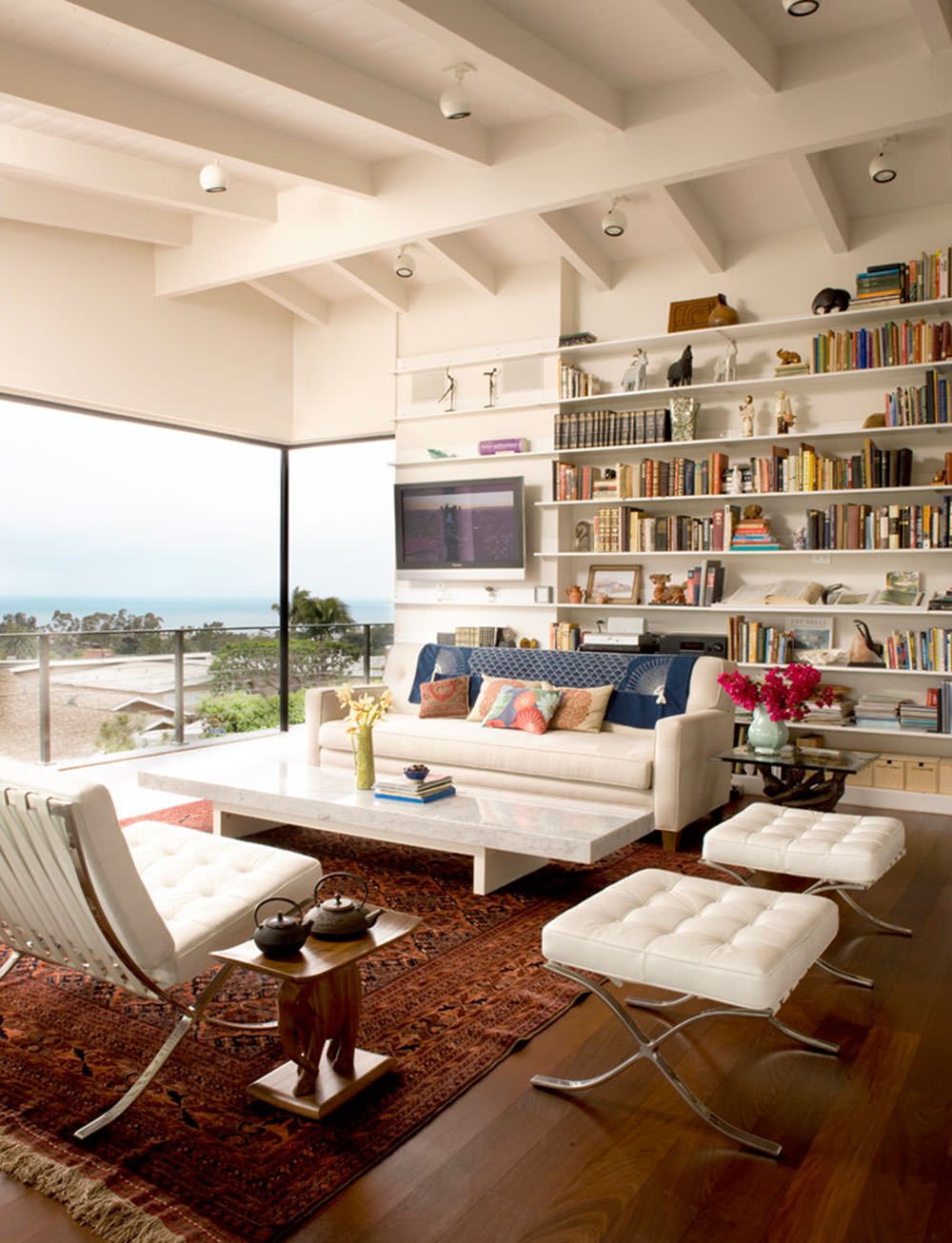 Soggiorno moderno con il soffitto a vista in legno verniciato bianco, in armonia con l'arredamento e la libreria aperta dello stesso colore - ispirazione soffitti decorati